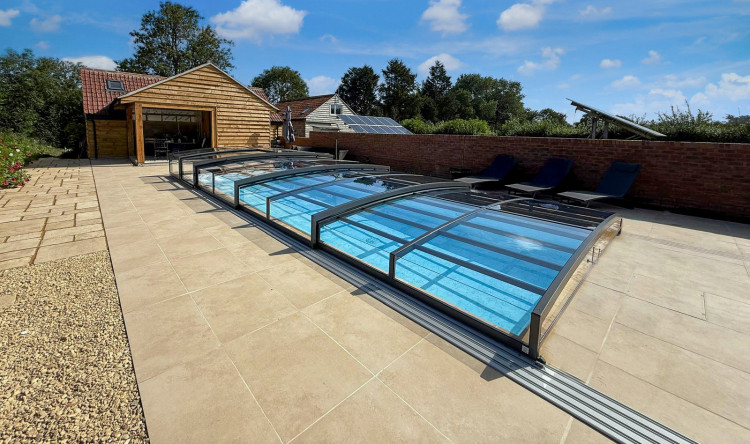 Low-profile ALUKOV telescopic pool enclosure with a single-sided track leaving the poolside area open and accessible